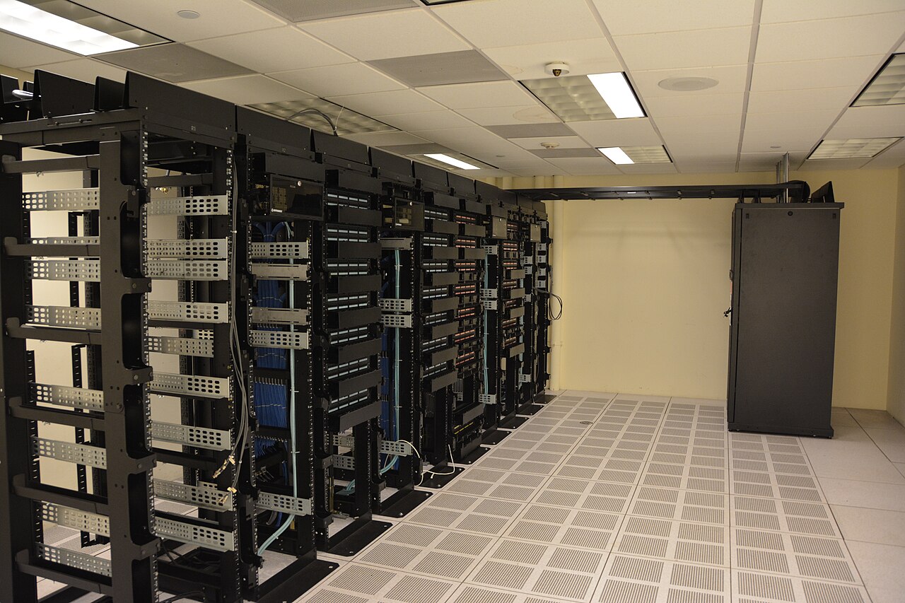 Rows of production server racks and network equipment inside a working data center.